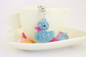 Dettaglio del portachiavi a forma di anatra con strass blu appeso a una tazza da caffè