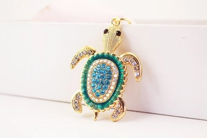 Vue détaillée du pendentif tortue avec strass bleus et finition dorée élégante