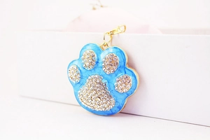 Detail of sky blue enamel pet paw pendant with sparkling rhinestones and gold lobster clasp