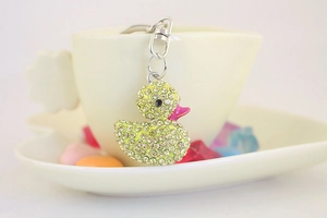 Dettaglio del portachiavi a forma di anatra con strass gialli su tazza bianca