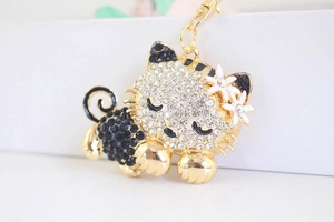 Macro shot of rhinestone-encrusted cat keychain with white flowers and gold-tone finish
