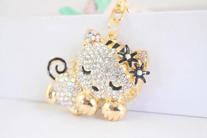 Detail of a gold cat keychain with crystals, black flowers and striped patterns