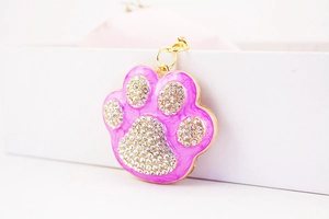 Detailed macro view of gold-plated pet paw pendant with pink enamel and white rhinestones