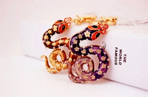Detail of crystal-encrusted snake keychains with colorful enamel plum flower patterns