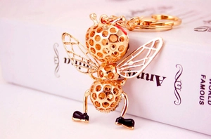 Détail du porte-clés abeille dorée avec structure en nid d'abeille creux sur livre