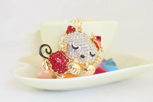 Detailed close-up of crystal-studded kitten keychain on elegant ceramic dish display