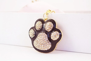 Close-up of a sparkling rhinestone paw print keychain with gold plating and lobster clasp