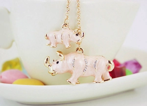 Détail de pendentifs rhinocéros en émail rose avec cristaux sur une chaîne dorée