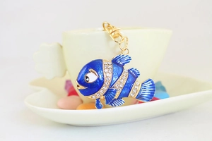 Détail d'un porte-clés poisson en émail bleu avec strass sur une tasse en céramique
