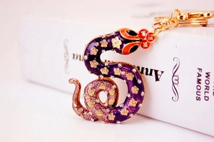 Detailed view of rhinestone zodiac snake keychain with purple enamel and gold finish