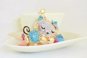 Detail shot of sleeping kitty pendant featuring blue rhinestones and gold alloy base