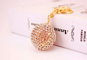 Detailed close-up of a sparkling crystal-encrusted sphere keychain with golden hardware