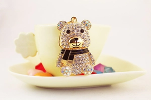 Dettaglio di un portachiavi panda dorato con strass scintillanti su una tazza da caffè