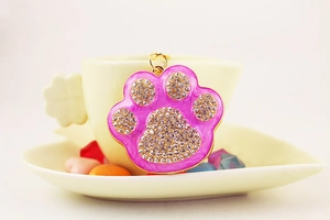 Close-up of golden alloy paw print keychain with pink enamel and sparkling rhinestones