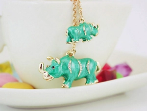 Détail de pendentifs rhinocéros en émail vert menthe avec strass sur chaîne dorée