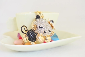 Close-up of sleeping cat keychain with white rhinestones and a small flower detail