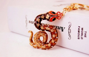 Close-up of golden zodiac snake keychain with brown enamel and sparkling rhinestones