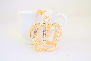 Détail d'un porte-clés couronne dorée avec strass et découpe en forme de petit coeur