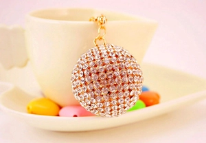Macro detail of a sparkling rhinestone crystal ball keychain on a warm cream coffee cup