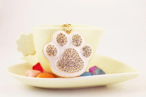 Detailed close-up of a sparkling rhinestone paw pendant on a golden keychain