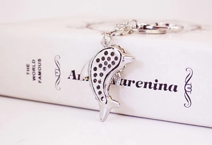 Detail of crystal dolphin keychain with silver rhinestones leaning against a book