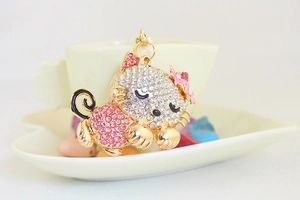 Close-up of a rhinestone sleeping cat keychain hanging on a porcelain cup handle