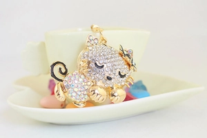 Macro shot of sleeping cat keychain with inlaid rhinestones on a white porcelain dish
