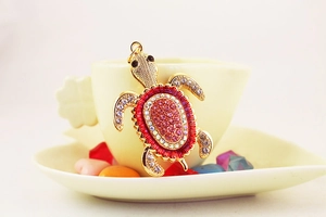 Gros plan d'un pendentif tortue dorée avec strass roses dégradés sur une tasse en céramique