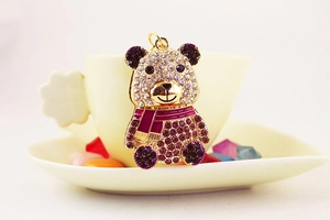 Dettaglio portachiavi panda con strass viola e anello dorato appoggiato su una tazza