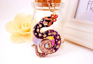 Detail view of purple enamel snake keychain with rhinestones on a glass jar