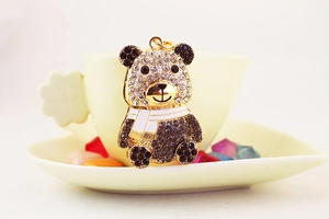Dettaglio del portachiavi panda con strass bianchi e neri su una tazza da caffè