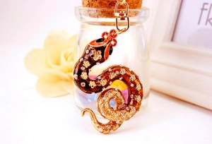 Detail of a gold zodiac snake keychain with colorful enamel and sparkling rhinestones