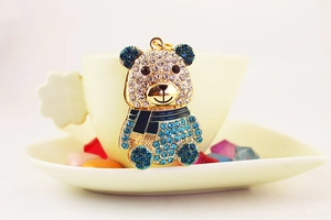 Vista dettagliata di un portachiavi a forma di panda con strass blu su una tazzina da tè bianca