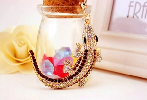 Detailed macro view of lizard keychain with embedded diamonds on a golden alloy metal base