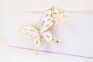 Detailed close-up of butterfly keychain with white enamel and rhinestones on gold alloy