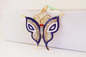 Detail of colorful butterfly keychain with rhinestones and blue enamel on a white box