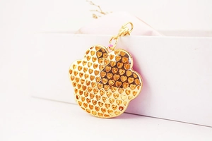 Detailed view of a gold-plated paw-shaped keychain with heart-shaped cutouts and spring clasp