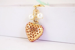 Detailed view of heart-shaped gold keychain with red rhinestones and faux pearls