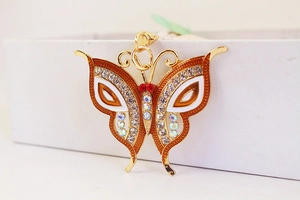 Macro detail of golden butterfly keychain featuring orange enamel wings and sparkling rhinestones