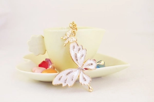 Detail of white butterfly keychain with sparkling rhinestones on golden frame