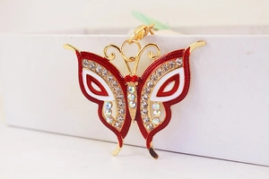 Detailed close-up of a red and gold butterfly charm with sparkling rhinestones and enamel