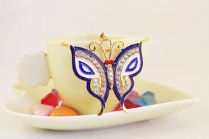 Detail of blue enamel butterfly keychain with sparkling rhinestones on ceramic cup