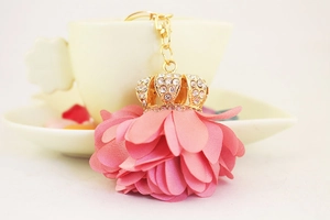 Close-up of pink flower ball keychain with a rhinestone crown and golden hardware