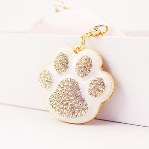 Sparkling rhinestone cat paw print keychain in gold alloy and white enamel