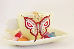 Detailed macro shot of red enamel butterfly keychain with sparkling rhinestones on ceramic