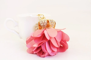 Close-up of pink fabric flower keychain with a gold rhinestone crown detail