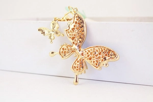 Detail of double butterfly gold keychain pendant with intricate honeycomb wing texture
