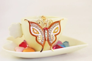 Detailed macro of gold butterfly keychain with sparkling rhinestones and white enamel