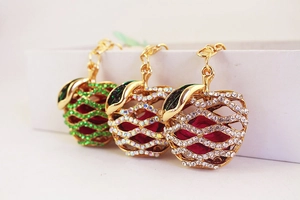 Detail of three apple-shaped keychains with rhinestones and gold hollow metal frame