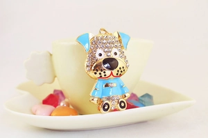 Détail d'un porte-clés chien en émail bleu orné de strass brillants sur une tasse